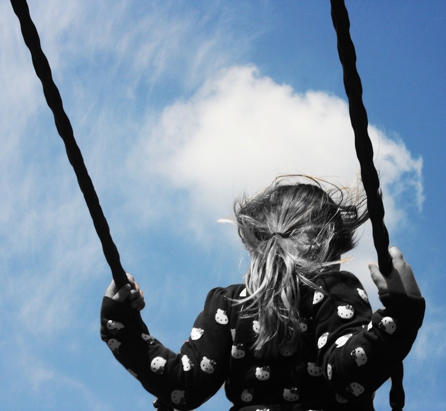 a young girl is swinging on a rope.