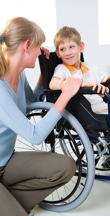 a woman helping a boy in a wheelchair.