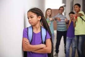Young girl getting teased by other children in school hallway