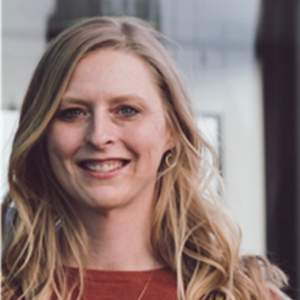 Portrait of a smiling blonde woman with wavy hair wearing a red top.